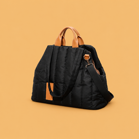 Black Waterproof Pet Travel Handbag with tan handles, centered for circular display on a warm beige-gold background | David's Pet Boutique
