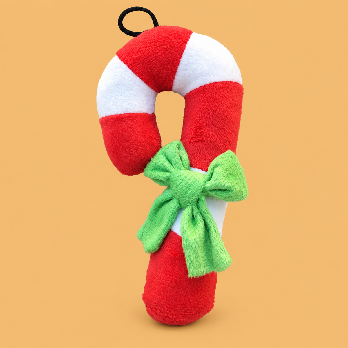 Christmas Candy Cane Plush Dog Toy — isolated product on a warm peach background